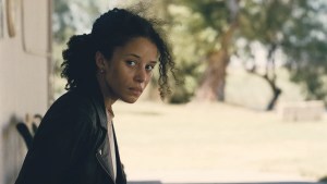 Chase Infiniti sits on a bench in "One Battle After Another"